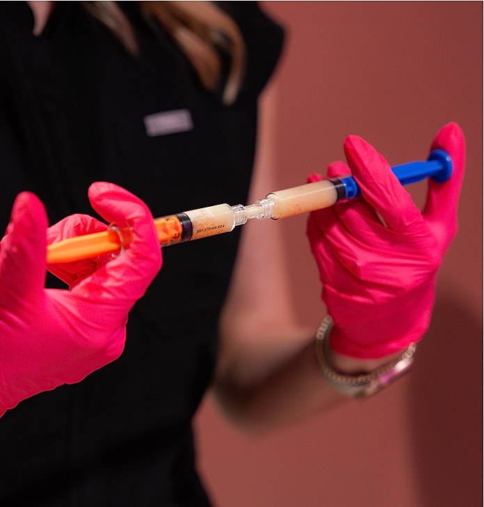 Person in gloves handling a syringe.