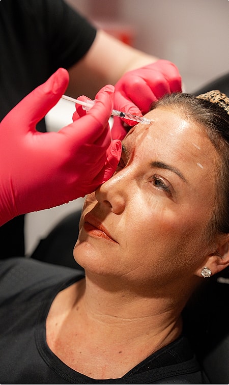 Woman using facial roller for skincare treatment.