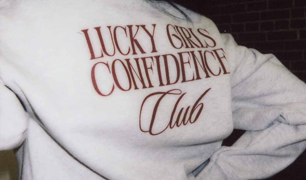 Sweatshirt with "Lucky Girls Confidence Club" design.