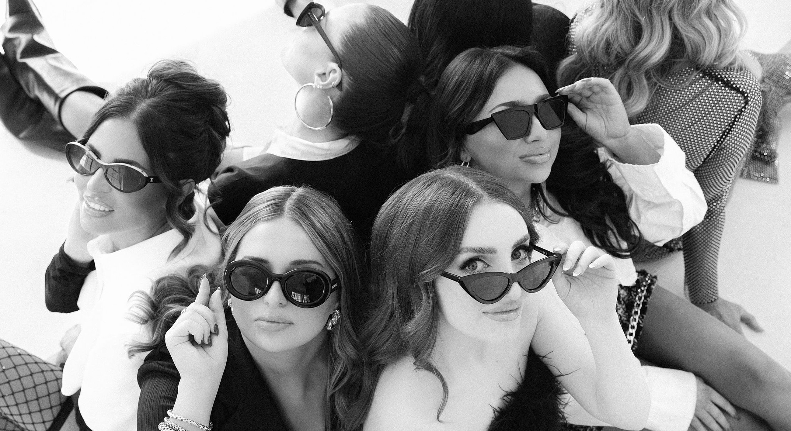 Group of stylish women wearing sunglasses, posing playfully.