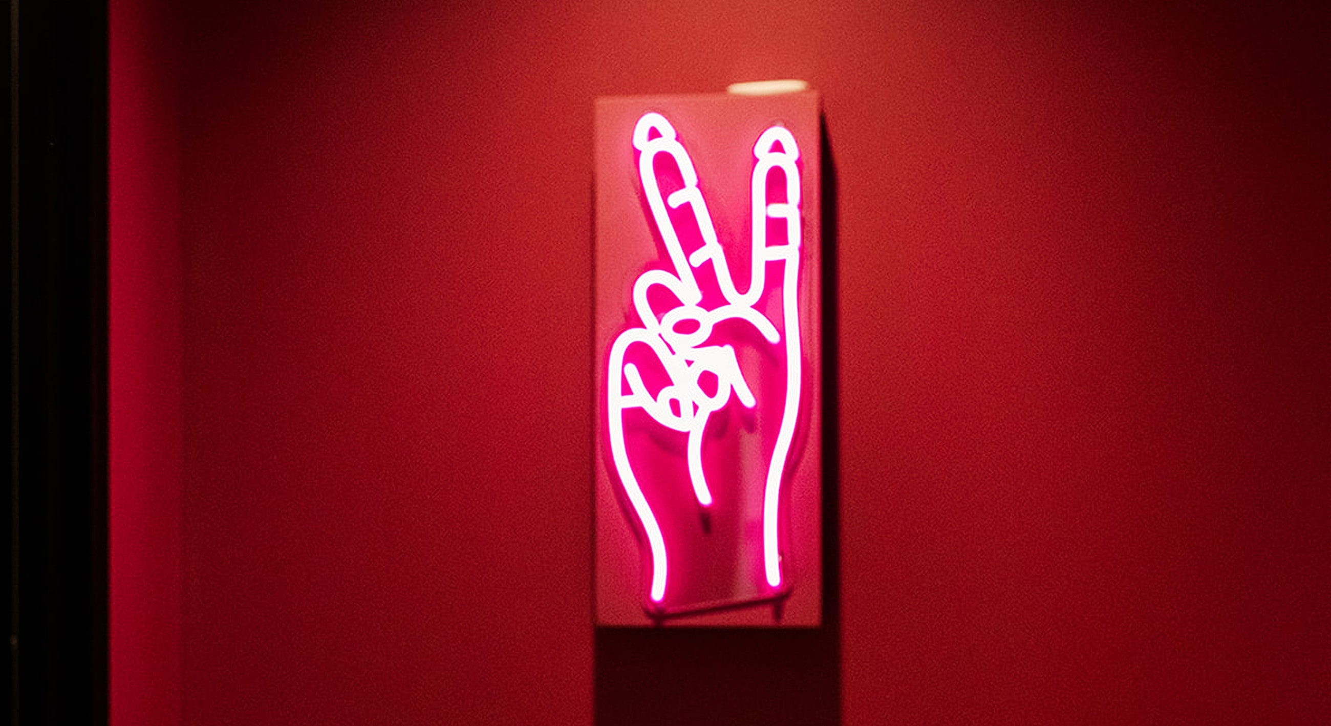 Neon sign of hand making peace gesture.
