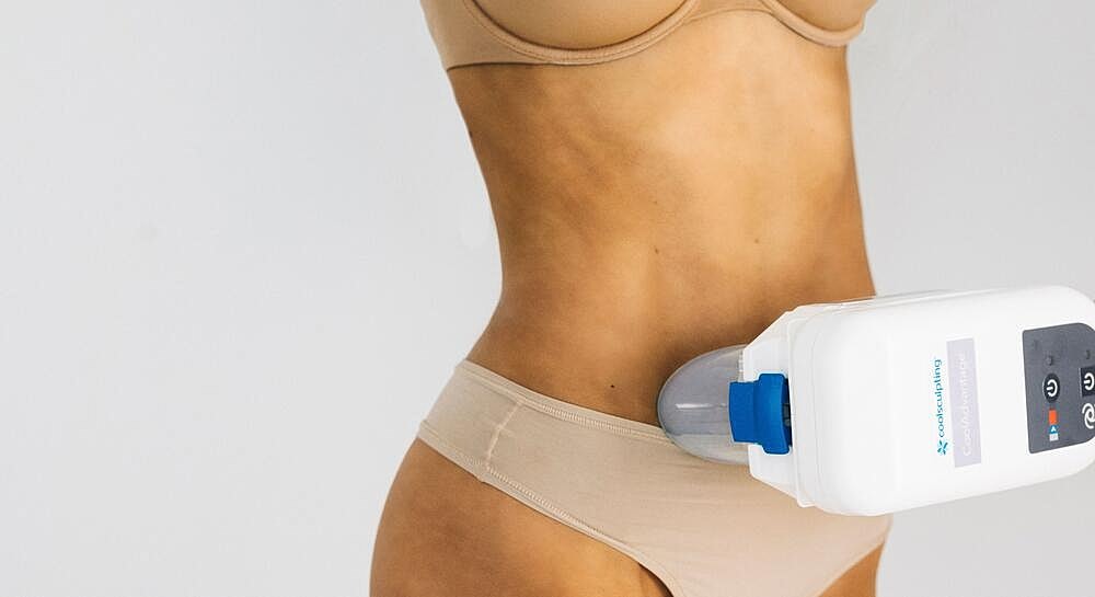 Woman using a body contouring device on waist.
