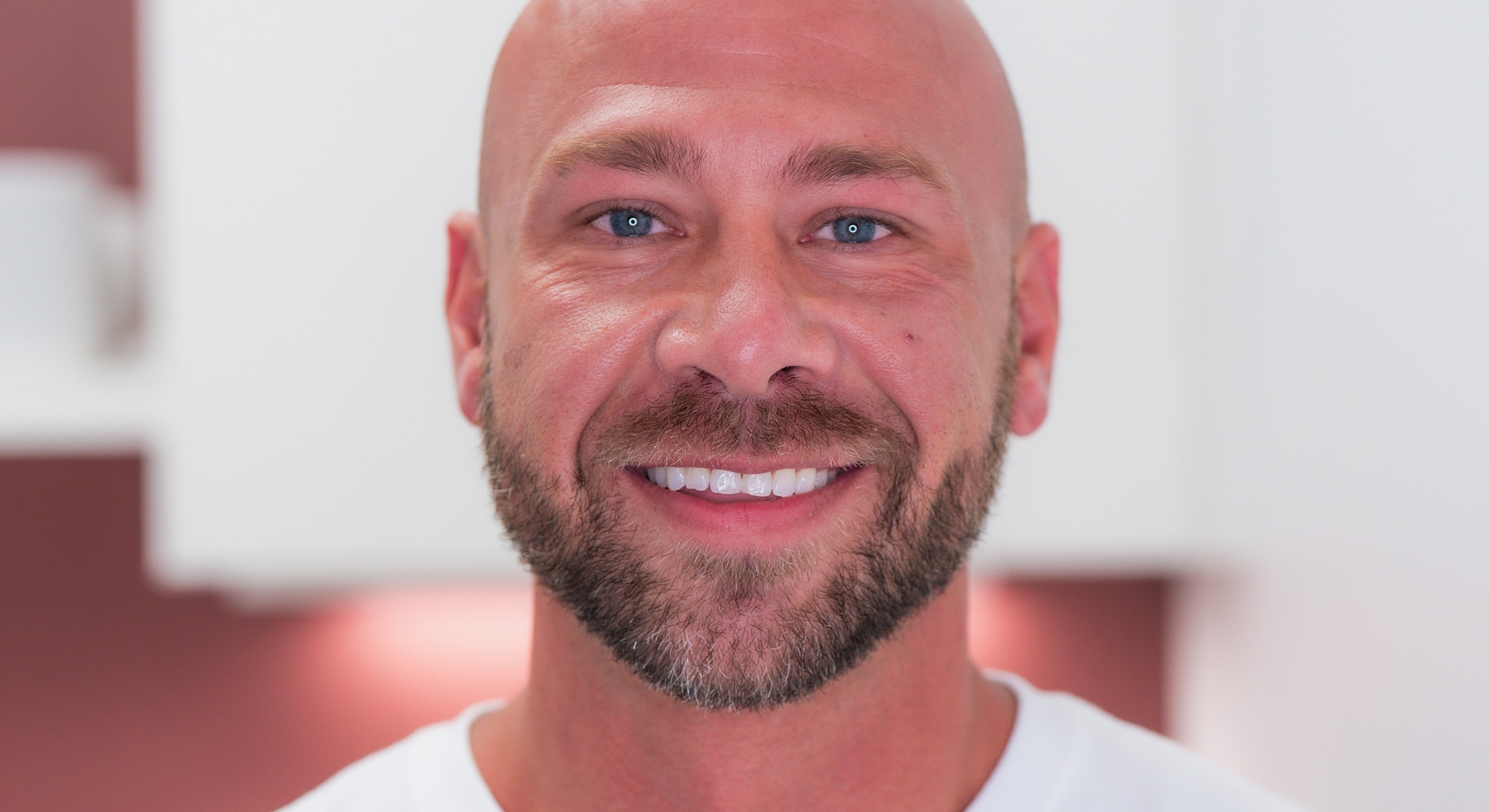 Smiling man with a beard in bright setting.